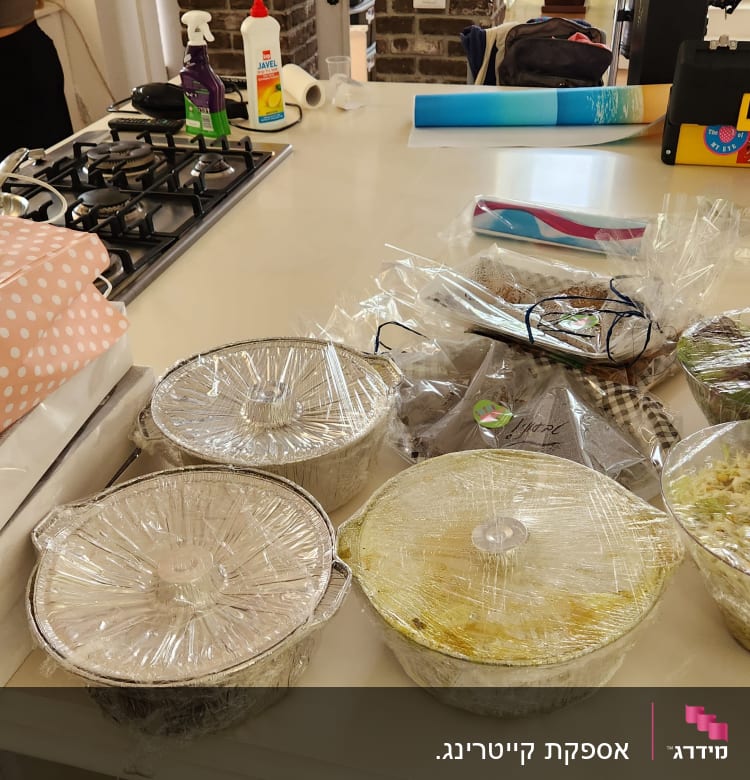 מגשי אוכל מכוסים בניילון על שולחן מטבח